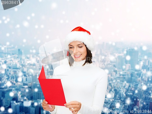 Image of smiling woman in santa hat with greeting card