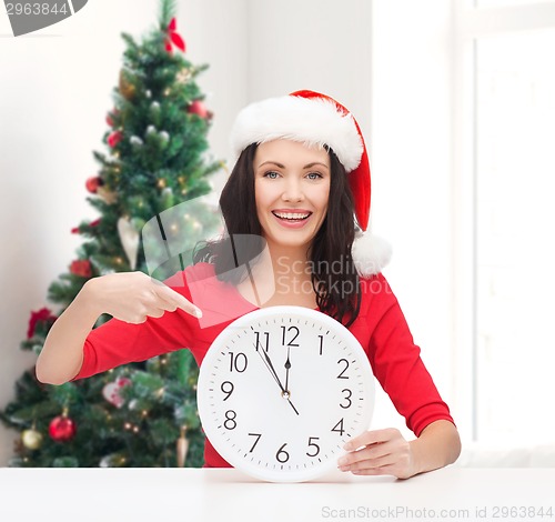 Image of smiling woman in santa helper hat with clock