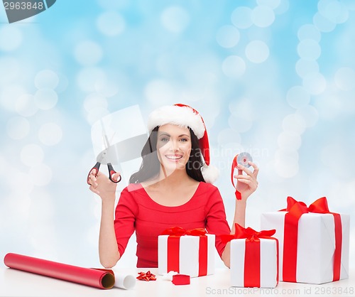 Image of smiling woman in santa helper hat packing gifts