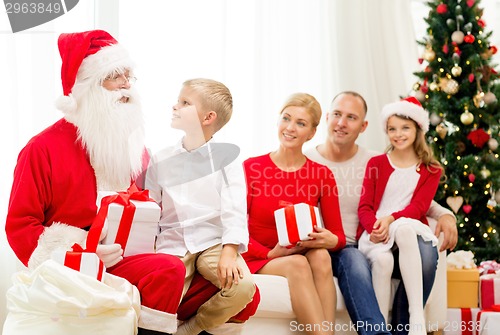 Image of smiling family with santa claus and gifts at home