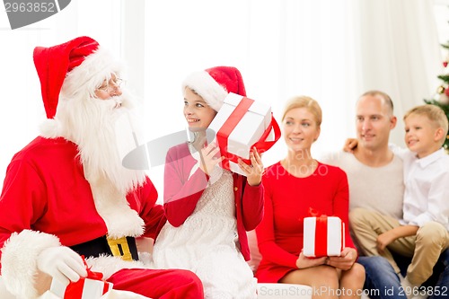 Image of smiling family with santa claus and gifts at home