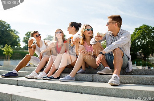 Image of group of smiling friends sitting on city square