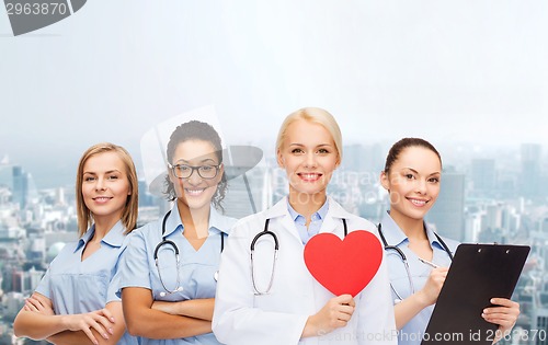 Image of smiling female doctor and nurses with red heart