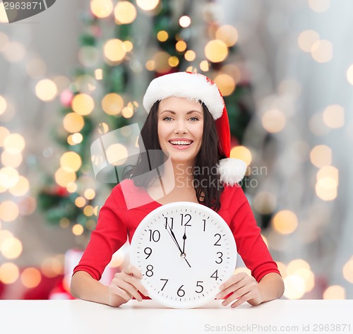 Image of smiling woman in santa helper hat with clock