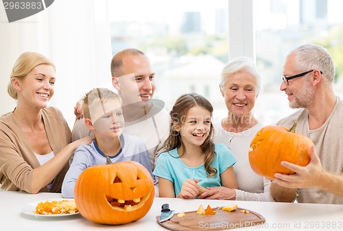 Image of happy family sitting with pumpkins at home