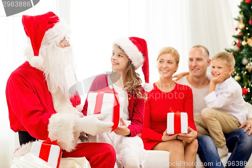 Image of smiling family with santa claus and gifts at home