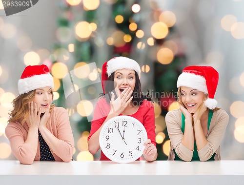 Image of smiling women in santa helper hats with clock