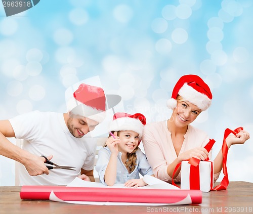 Image of happy family in santa helper hats packing gift