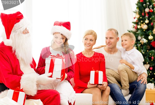 Image of smiling family with santa claus and gifts at home