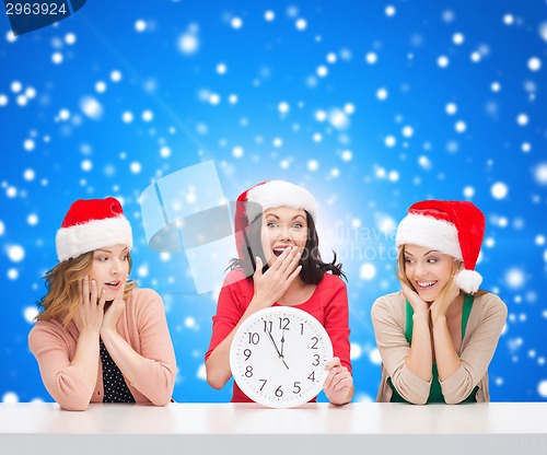 Image of smiling women in santa helper hats with clock