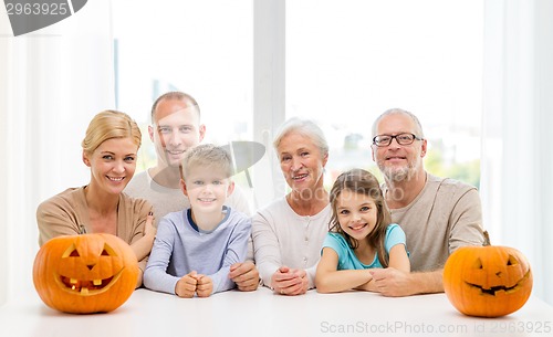 Image of happy family sitting with pumpkins at home