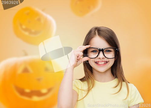 Image of smiling girl in glasses over pumpkins background