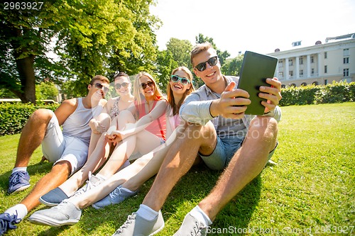 Image of smiling friends with tablet pc computer in park