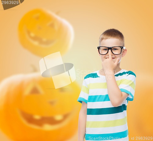 Image of smiling boy in glasses over pumpkins background