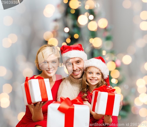 Image of happy family in santa helper hats with gift boxes