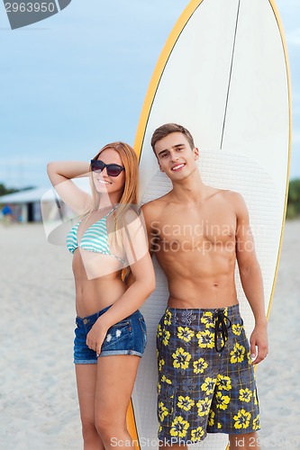 Image of smiling couple in sunglasses with surfs on beach