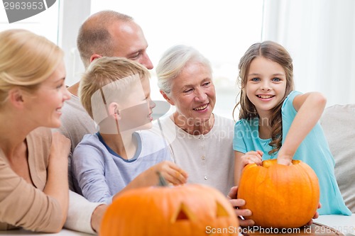 Image of happy family sitting with pumpkins at home