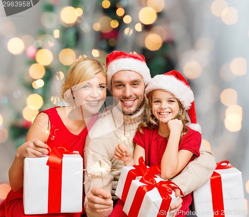 Image of happy family in santa helper hats with gift boxes