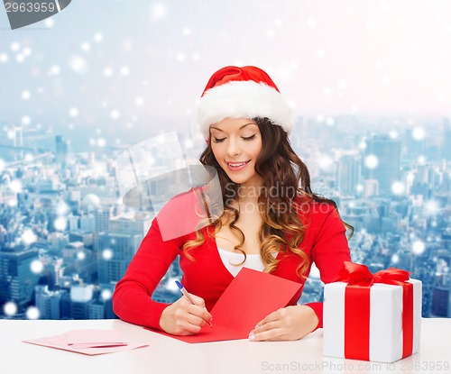 Image of smiling woman with gift box writing letter