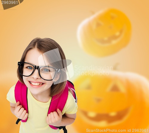 Image of smiling girl in glasses over pumpkins background