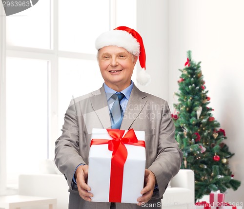 Image of smiling man in suit and santa helper hat with gift