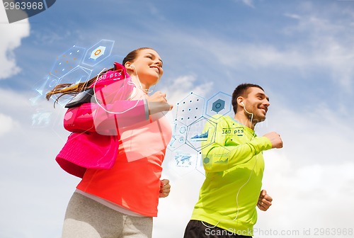 Image of smiling couple with earphones running outdoors
