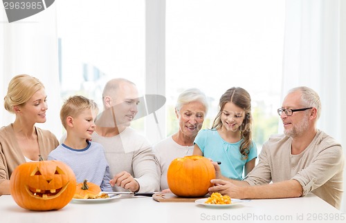 Image of happy family sitting with pumpkins at home