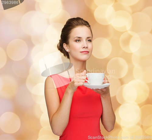 Image of smiling woman in red dress with cup of coffee