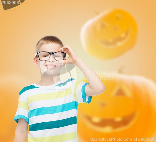 Image of smiling boy in glasses over pumpkins background