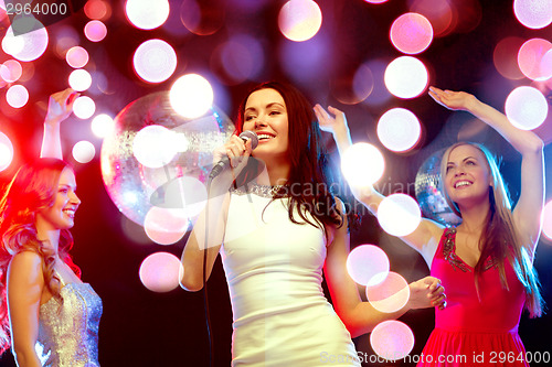 Image of three smiling women dancing and singing karaoke