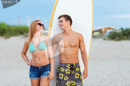 Image of smiling couple in sunglasses with surfs on beach