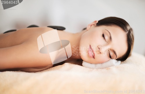 Image of beautiful woman in spa salon with hot stones