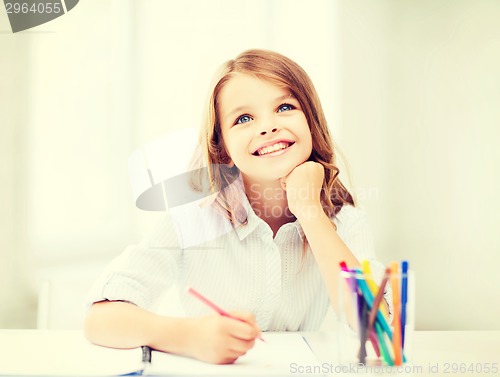 Image of smiling little student girl drawing at school