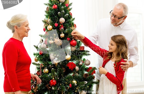 Image of smiling family decorating christmas tree at home