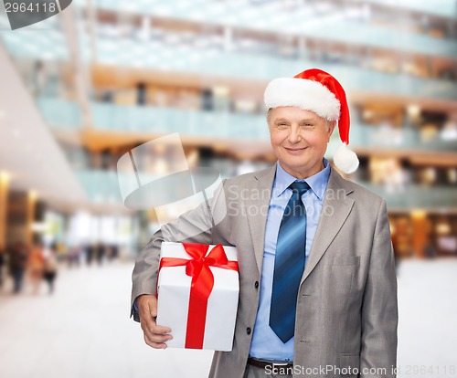 Image of smiling man in suit and santa helper hat with gift