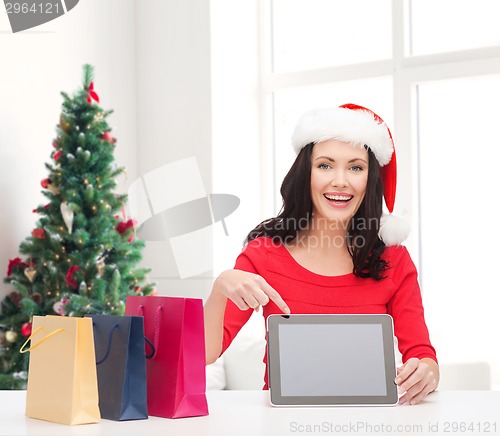 Image of smiling woman in santa hat with bags and tablet pc