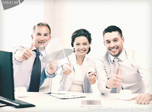 Image of business team showing thumbs up in office