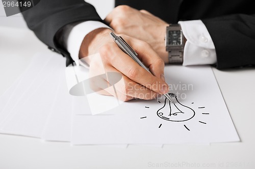 Image of close up of male hands with pen drawing bulb