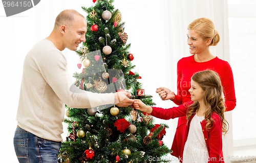 Image of smiling family decorating christmas tree at home