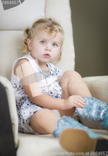 Image of Blonde Haired Blue Eyed Little Girl Putting on Cowboy Boots