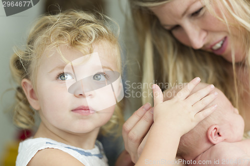 Image of Young Mother Holds Newborn Baby Girl as Young Sister Looks