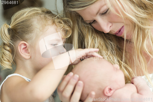 Image of Young Mother Holds Newborn Baby Girl as Young Sister Looks