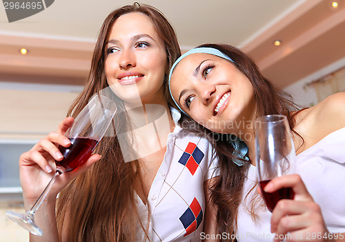 Image of Happy girlfriends with glasses on kitchen