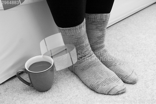 Image of Hot drink on the floor by feet in socks