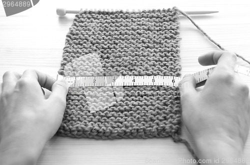 Image of Two hands measuring knitting in inches