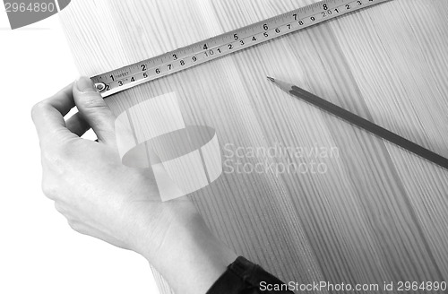 Image of Using a steel tape measure on a wooden board 