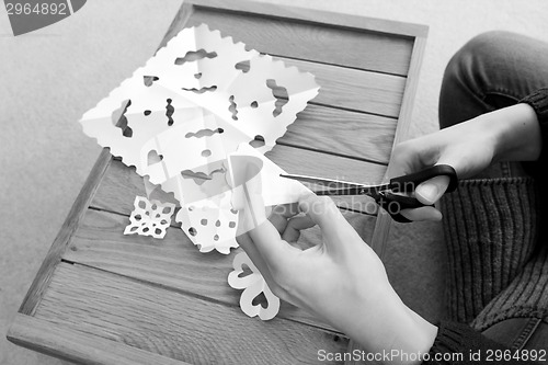 Image of Woman cutting paper into snowflake designs