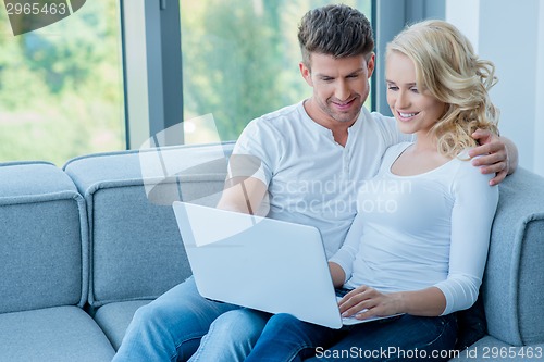 Image of Young couple sitting sharing a laptop computer