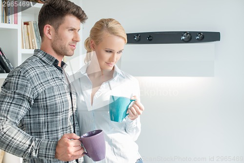 Image of Young couple standing drinking coffee