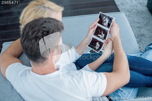 Image of Sweet Couple on Couch Looking Ultrasound Photos